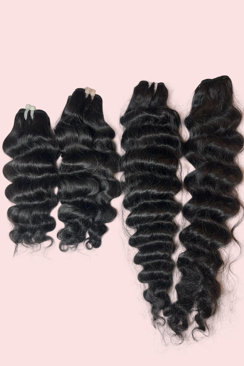 Four bundles of 1B,  wave hair extensions laid out on a white fabric background, including different lengths and densities. On sample and display sale as a bundle of four wefts laid out.